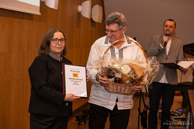 Kazimierz Pichalak odbierał dyplom Ambasadora Karkonoskiej Marki Lokalnej w koszuli z haftem zachełmiańskim. Dyplom wręczała Dorota Goetz, Lokalnej Grupy Działania Partnerstwo Ducha Gór