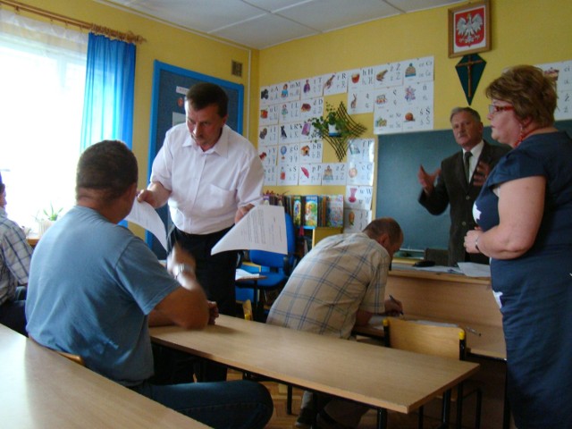 Sołtys Tropia (z lewej) pokazuje uczestnikowi zebrania dokumenty dotyczące likwidacji szkoły