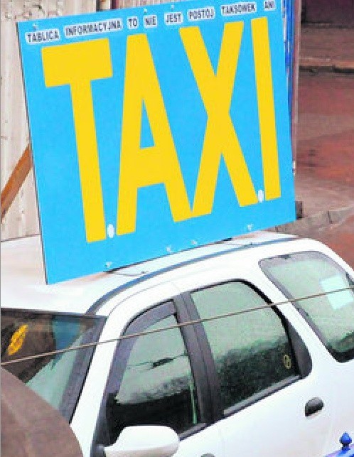 Pseudotaksówkarze ustawiają na samochodzie szyld "Taxi"