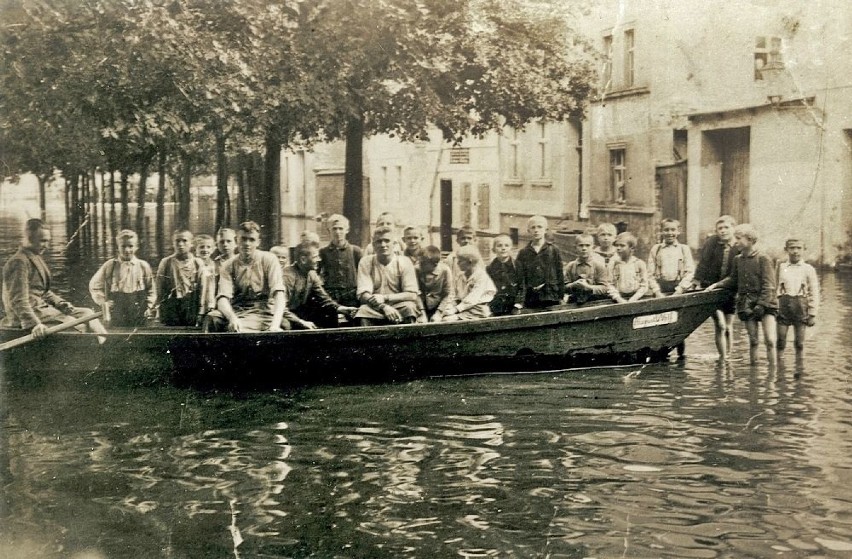 Na zdjęciu grupa osób stojąca w wodzie oraz siedząca na...