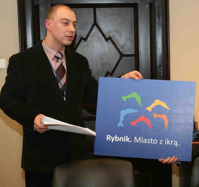 Krzysztof Jaroch prezentuje tablicę z nowym logo