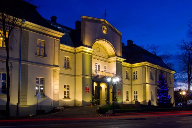 Podświetlona frontowa fasada tworoskiego pałacu, w którym mieście się urząd gminy