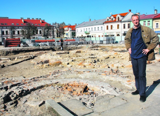 Jerzy Roś, archeolog, stoi nad odkrywanym ratuszem. Na pierwszym planie wieża ciśnień