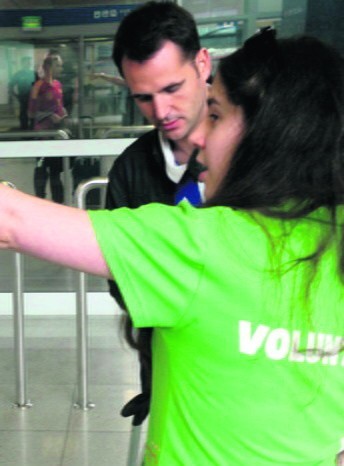 Na lotnisku wolontariusze pokazują turystom, gdzie znajdą...
