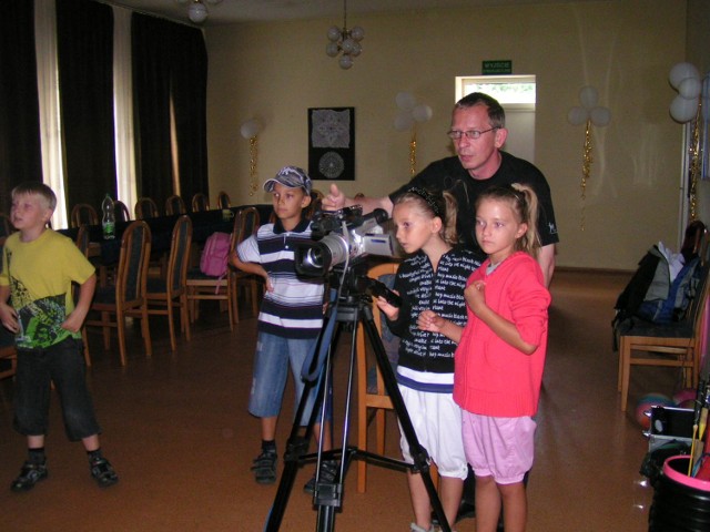 Adam Sadura pokazuje dzieciom jak obsługiwać kamerę