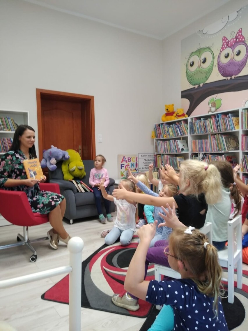 Przedszkolaki wśród regałów z książkami. Pierwsze wizyty w bibliotece.