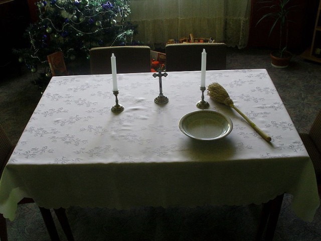 St&oacute;ł przygotowany na wizytę duszpasterską: świece, kropidło, krzyż, woda święcona