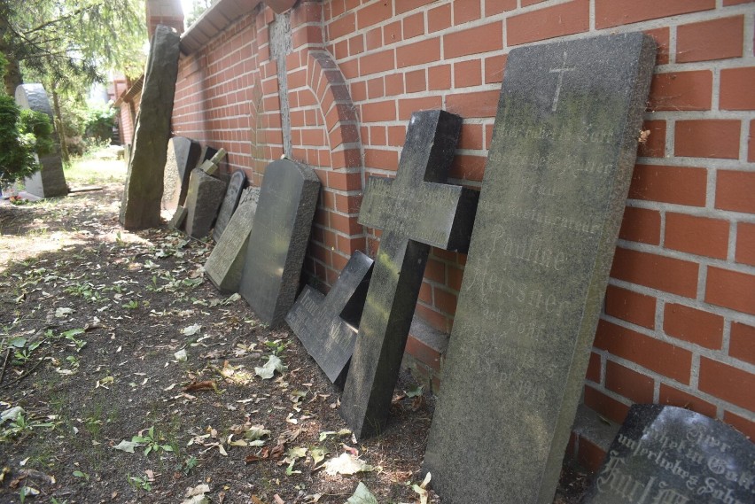 Poniemieckie płyty nagrobne stoją oparte o mur cmentarza...