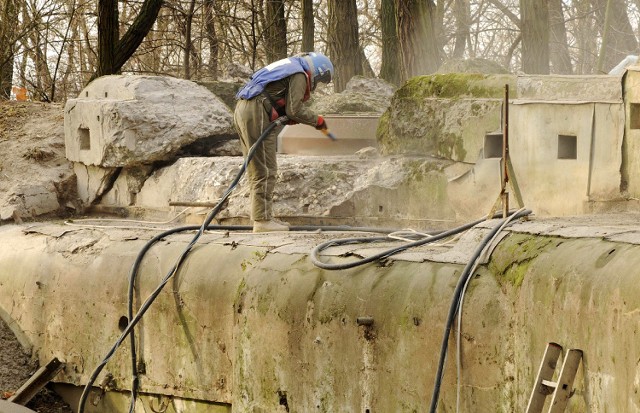 Pracownicy oczyszczają z zewnątrz metalowe i betonowe konstrukcje