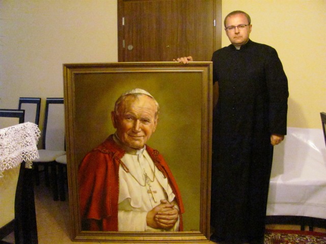 Ksiądz proboszcz Alfred Berlak prezentuje portret Jana Pawła II, który upamiętni nadanie patrona kaliskiej parafii