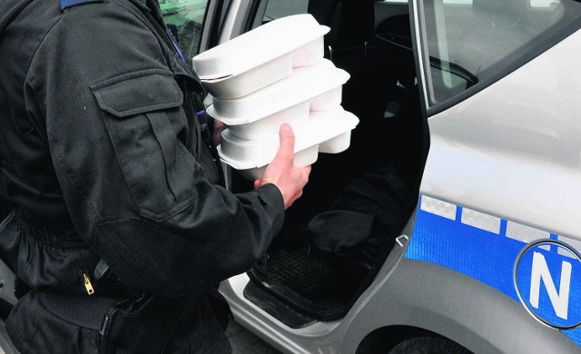 Policjanci przewożą posiłki przygotowane przez szpital na tylnym siedzeniu radiowozu