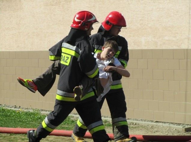 Strażacy wynoszą ucznia pozorującego zatrucie dymem