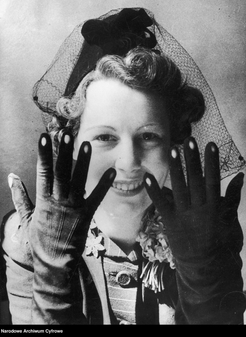 Kobieta prezentuje Ostatni krzyk mody rękawiczki z otworami, przez które widać polakierowane paznokcie. Moda angielska