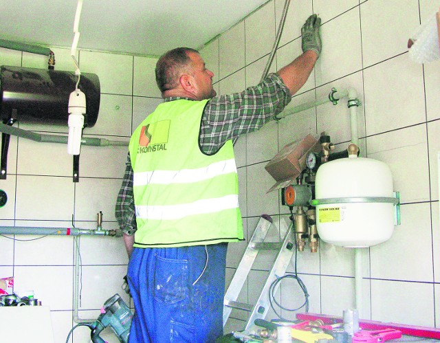 Pracownik firmy Ekoinstal podłącza kolektor do zbiornika z wodą u mieszkańca Sielc