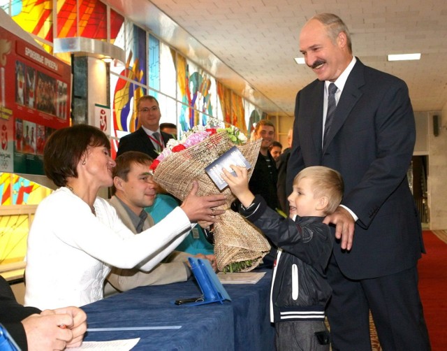Prezydent Aleksander Łukaszenka i jego młodszy syn Mikołaj wręczaja kwiaty członkini komisji wyborczej w Mińsku