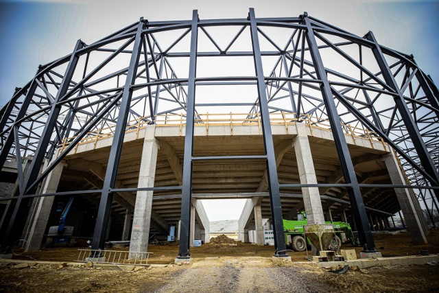 Najbardziej widoczne na placu budowy są metalowe konstrukcje zadaszenia na hali sportowej i Stadionie. Wewnątrz widać już żelbetowe konstrukcje schodów.

Zobacz kolejne zdjęcia. Przesuwaj zdjęcia w prawo - naciśnij strzałkę lub przycisk NASTĘPNE