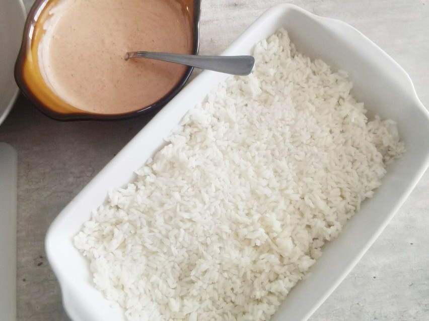 W naczyniu żaroodpornym wyłóż warstwę ryżu. Posmaruj go...