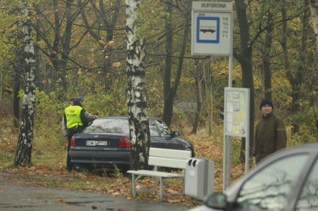 Cmentarz przy ulicy Bardzkiej. Kierowca opla astry za parkowanie w zagajniku za przystankiem autobusowym zapłaci co najmniej stuzłotowy mandat.