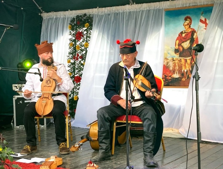 Muzyk z lewej strony gra na suce biłgorajskiej