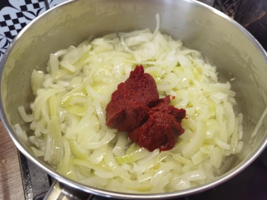 Dodaj do cebuli pomidorowy koncentrat i wodę. Wymieszaj.