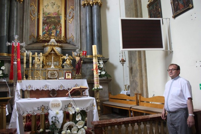 Ksiądz proboszcz parafii pw. Przemienienia Pańskiego w Ogrodzieńcu Jacek Furtak stoi przy ołtarzu i ekranie ledowym.