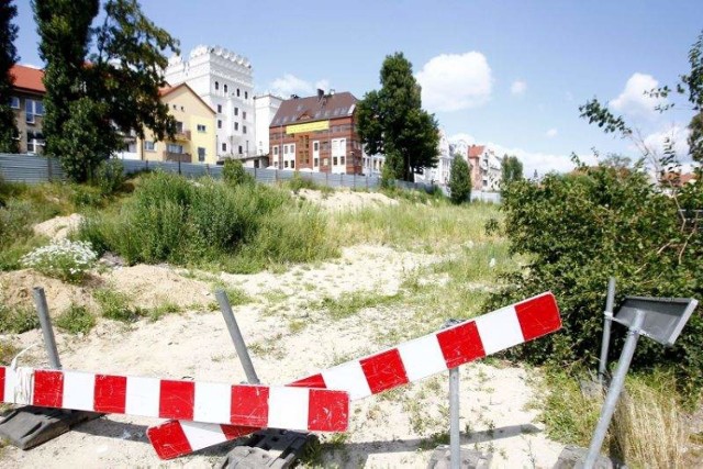 Blaszany płot ogradza teren po byłym hotelu „Arkona”. Do nieruchomości należy też 1/3 pl. Nowy Rynek, na którym stoją dziś jeszcze samochody. Co tu powstanie - szkaradek czy duma miasta?