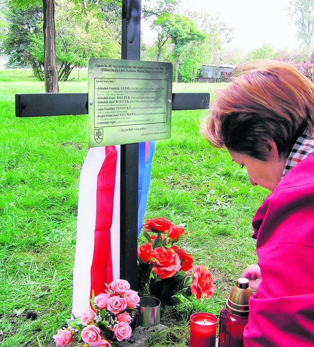 Wnuczka Frantiszka Szebo zapala znicz pod krzyżem na zapomnianej nekropolii