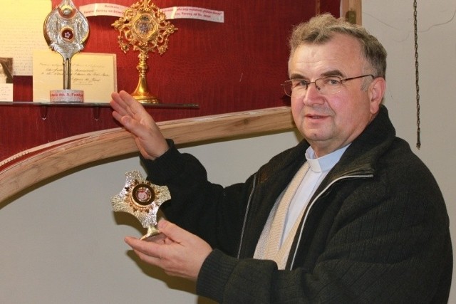 Proboszcz Teodor Suchoń trzyma relikwie świętych w kościelnej gablocie