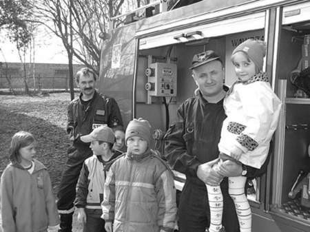 Młodszy aspirant Robert Ostaszewski (z dzieckiem na ręku) 
i młodszy ogniomistrz Stanisław Gibałka pokazują 
maluchom strażacki samochód ratowniczy.
