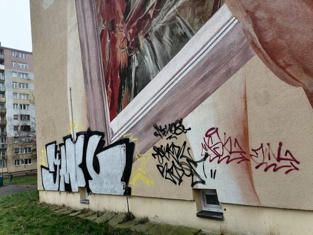 Dolną część pracy van Heltena zamalowano graficiarskimi tagami. Na obu budynkach