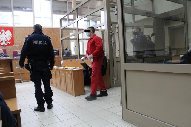 Jacek W. ps. Małpa na sali rozpraw krakowskiego sądu. Jest skuty łańcuchami i pilnowany przez policjantów uzbrojonych  broń maszynową. Jego oskarżenie było możliwe dopiero po ekstradycji z Wielkiej Brytanii, gdzie się ukrył przed polską policją i prokuraturą