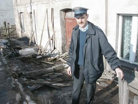 Starszy aspirant Aleksander Koszałka pokazuje skutki uderzenia mercedesa w dom.