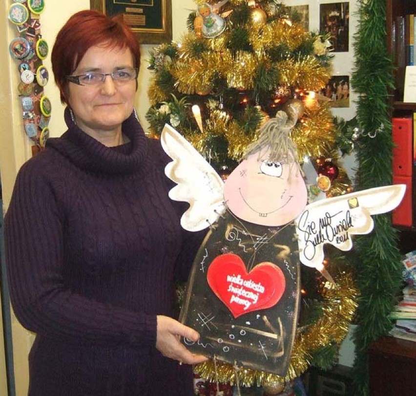 Teresa Woźniak prezentuje drewnianego anioła z podpisem...