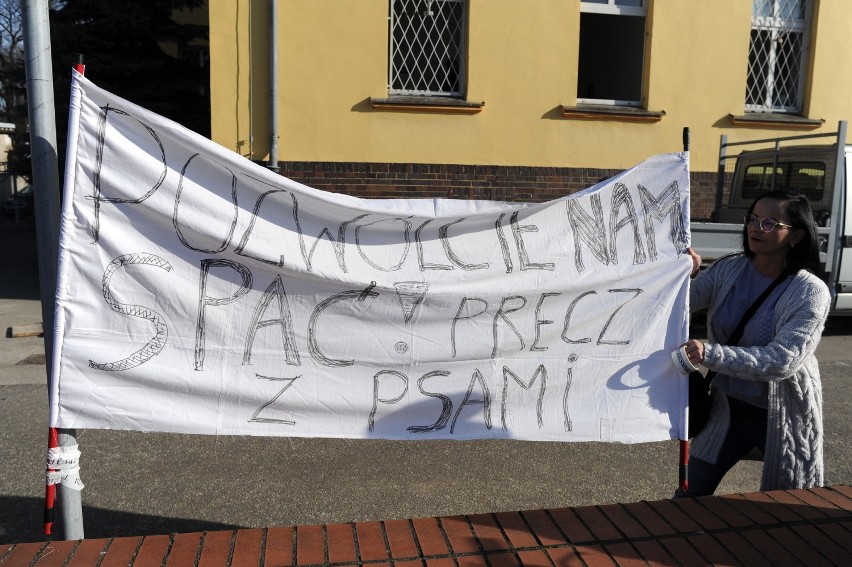 Mieszkanka Leszna protestuje pod komendą policji z transparentem