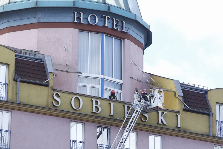 Akcja ratunkowa pod hotelem Radisson Blu Sobieski. Po gzymsie budynku chodzi człowiek 