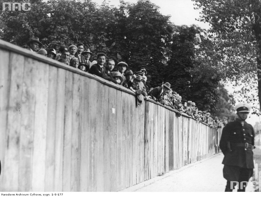 1929 r. Kibice oglądają zawody sportowe zza ogrodzenia. Na...