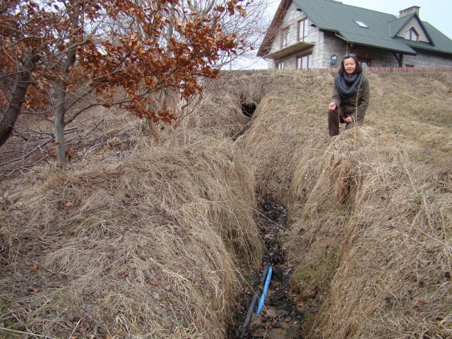 Małgorzata Sulka pokazuje kable, które na jej działce w Łękawicy wypłukała woda
