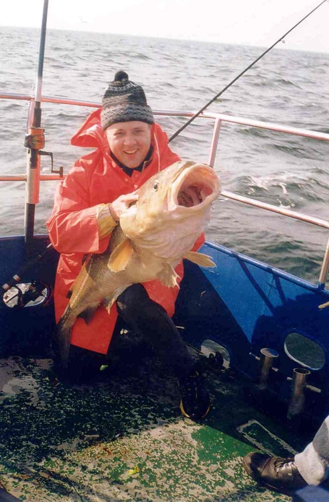 Zdjęcie nr 1: Zdjęcie zrobione podczas morskiej wyprawy wędkarskiej, na której Paweł Moczyński złowił swoją największą do tej pory rybę tj. dorsza o wadze 20,5 kg. Ryba została złowiona w Morzu Bałtyckim w okolicach Łeby na jednostce "Księżna Łeby" w dniu 1 maja 2004 roku tj. w dniu wejścia Polski do Unii Europejskiej, dlatego też została nazwana Unijnym Dorszem.
