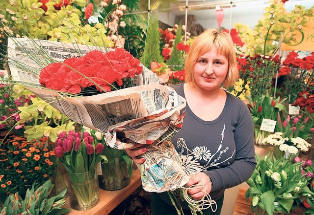 Beata Gronkiewicz prezentuje bukiet goździków zawinięty w gazetę. To żart, nawiązujący do czasów komuny.