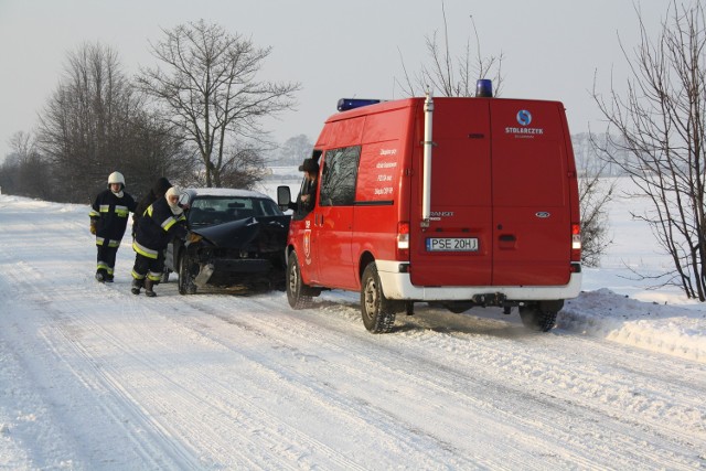 Strażacy, by udrożnić ruch ręcznie odciągali auto biorące udział w wypadku na pobocze.