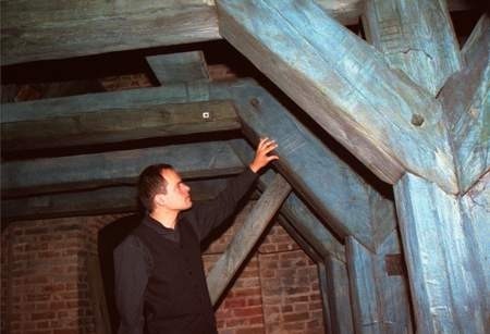 Ksiądz Wawrzyniec Ciesielski pokazuje część zabytkowej więźby dachowej.