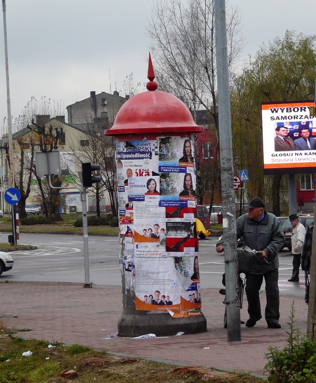 Słup na klepsydry przy ulicy Piastowskiej oklejony plakatami