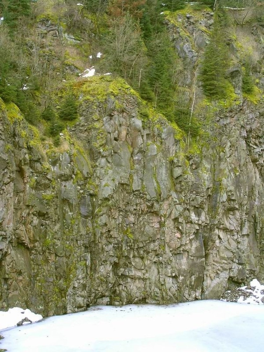 Pionowa ściana schodzi do zamarzniętego stawu. Natura...