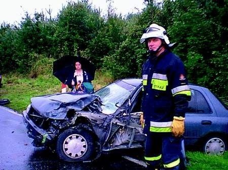 Żona kierowcy nissana i rawicki strażak - mł. ogn. Andrzej Wosiak przy zniszczonym samochodzie.