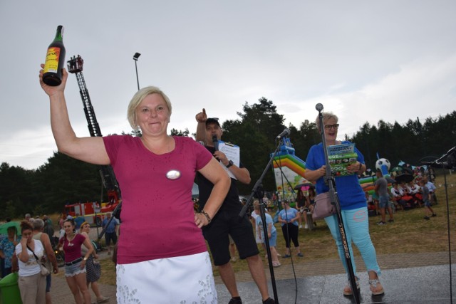 Pani Agnieszka Śmiałkowska podczas festynu w Juchowie licytuje butelkę wina Mamrot na odbudowę iglicy