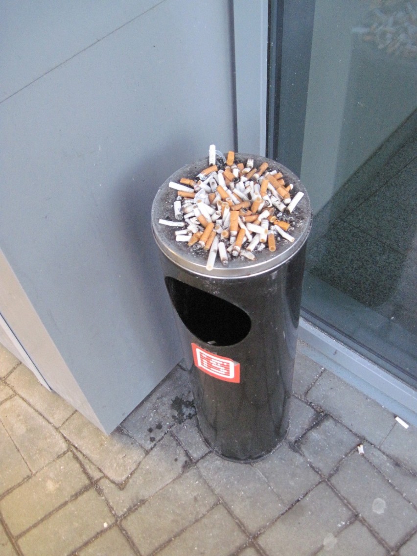 Kłęby dymu papierosowego przed wejściem do marketu "Stokrotka" w Lublinie 