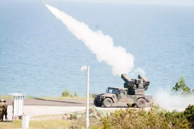 W Ustce zakończyły się Tobruq Legacy 2019, czyli największe ćwiczenia naziemnej obrony powietrznej państwa Paktu Północnoatlantyckiego. NATO wykonało około 160 strzelań bojowych. Te najbardziej widowiskowe miały miejsce w poniedziałek.


 
Właśnie zakończone ćwiczenia Tobruq Legacy 2019, które były największym testem przeciwlotników NATO. Przez dwa pierwsze tygodnie czerwca na teren Centralnego Poligonu Sił Powietrznych sprawdzali oni swoje umiejętności podczas ostrych strzelań. TOLY19 realizowano na poziomie sztabowym i poligonowym. W tym ostatnim przypadku z udziałem około 4 800 osób personelu i 1200 jednostek sprzętu. 

Do Ustki przyjechali żołnierze z Grupy Wyszehradzkiej, Niemiec, Estonii, Litwy, Holandii, Wielkiej Brytanii, Rumunii i Stanów Zjednoczonych. Na poligonie znalazły się wiekowe zestawy Osa, Newa, Kub, rumuńskie Hawki, nowoczesne NASAMS przywiezione przez Holendrów, a nawet Patrioty Bundeswehry. W sumie, całe spektrum różnych zestawów przeciwlotniczych od tych krótkiego po średni zasięg. W poniedziałek wojskowi strzelali pokazowo, przed dowództwem i mediami. Dodajmy, że z różnym skutkiem. Skutecznie trafiali Węgrzy, Słowacy i Rumuni. Jednak nie każdy Stinger odpalony przez amerykańskich żołnierzy osiągnął cel. - Obrona powietrzna jest priorytetem, jeśli chodzi rozwój sił Rzeczypospolitej - powiedział obserwujący ćwiczenia gen. Rajmund Andrzejczak, szef sztabu WP. - Zatem to ćwiczenie, w takiej skali i umiędzynarodowieniu jest najlepszym miejscem, aby na ten temat rozmawiać. Biorą udział wszystkie kraje flanki wschodniej, z którymi od dłuższego czasu rozmawiamy szeroko na temat budowy architektury bezpieczeństwa. Nie, tylko jeśli chodzi i przestrzeń powietrzną.

Co ciekawe, podczas ćwiczenia Tobruq Legacy 2019 sprawdzano konfigurację systemów teleinformatycznych oraz łączności. Przeprowadzono około 160 strzelań bojowych przy wsparciu powietrznymi systemem wczesnego ostrzegania AWACS, czyli samolotu boeinga z charakterystycznym okrągłym radarem kadłubem samolotu. Patriotów nie odpalano.