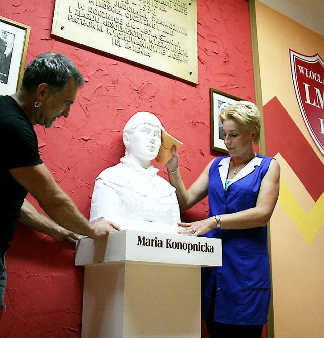Anna Krasińska i Krzysztof Chełminiak ustawiają w holu rzeźbę patronki szkoły.
