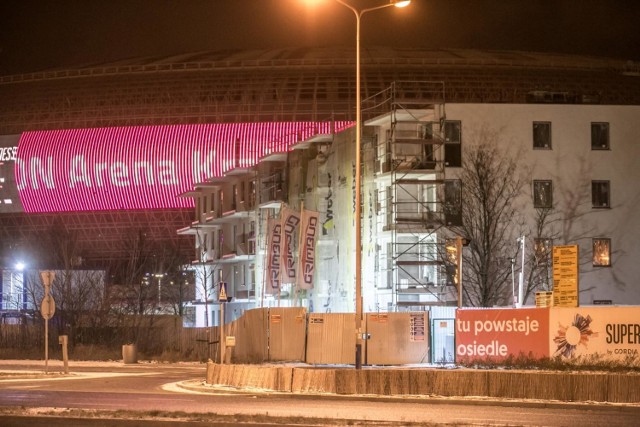 Taki widok na Tauron Arenę Kraków wyłania się od strony alei Pokoju i jej skrzyżowania z ulicą Lema. Budynki zasłaniają halę. Ta z kolei wieczorami z powodu ekranu LED, oświetli okna bloków