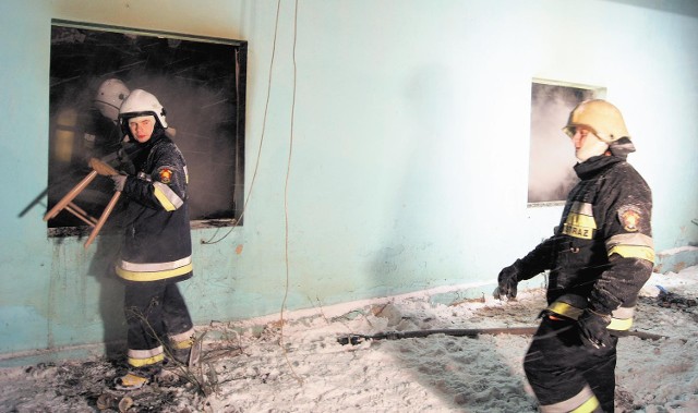 Strażacy wynoszą z domu spalone meble